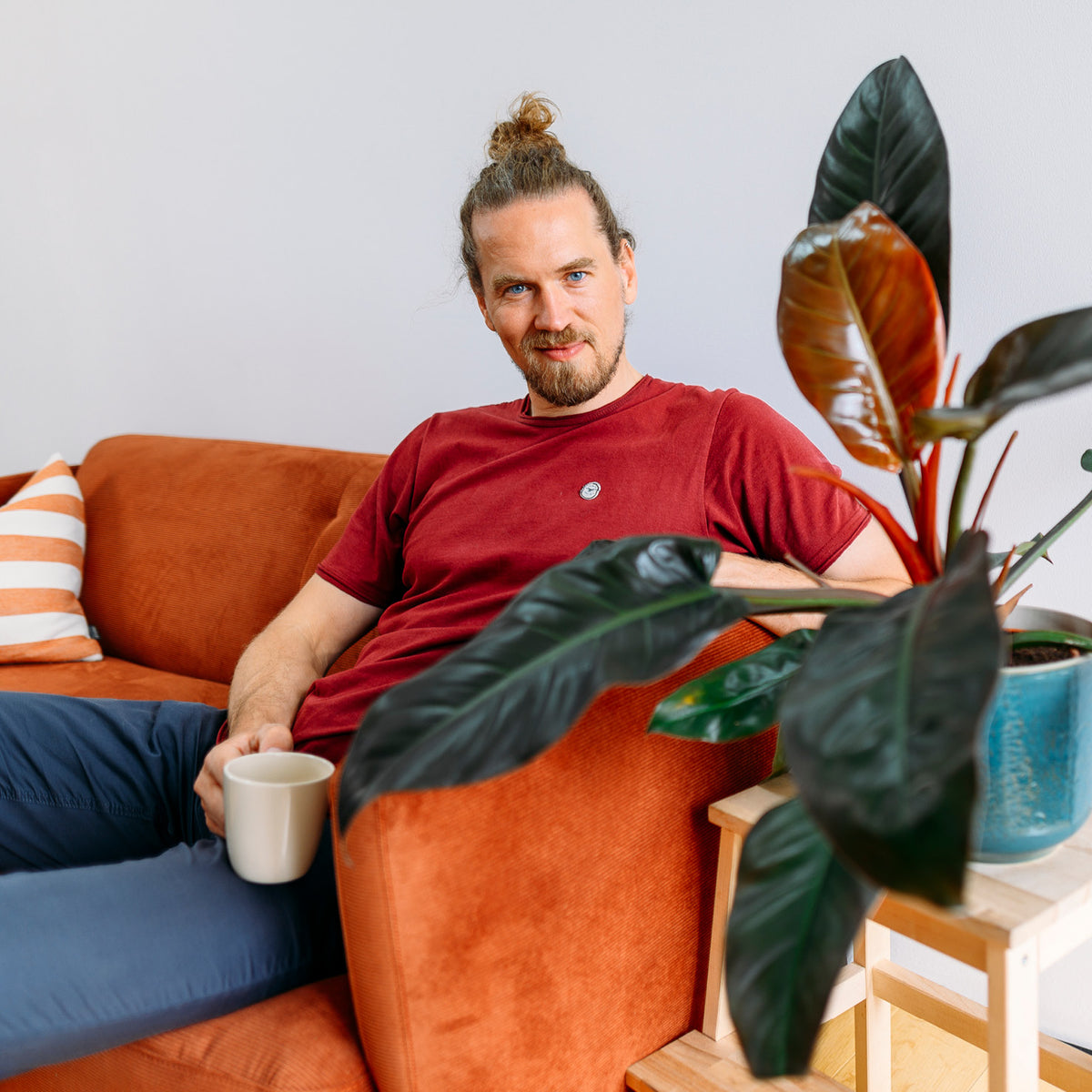 Mann mit Philodendron 'Imperial Red' im Wohnzimmer